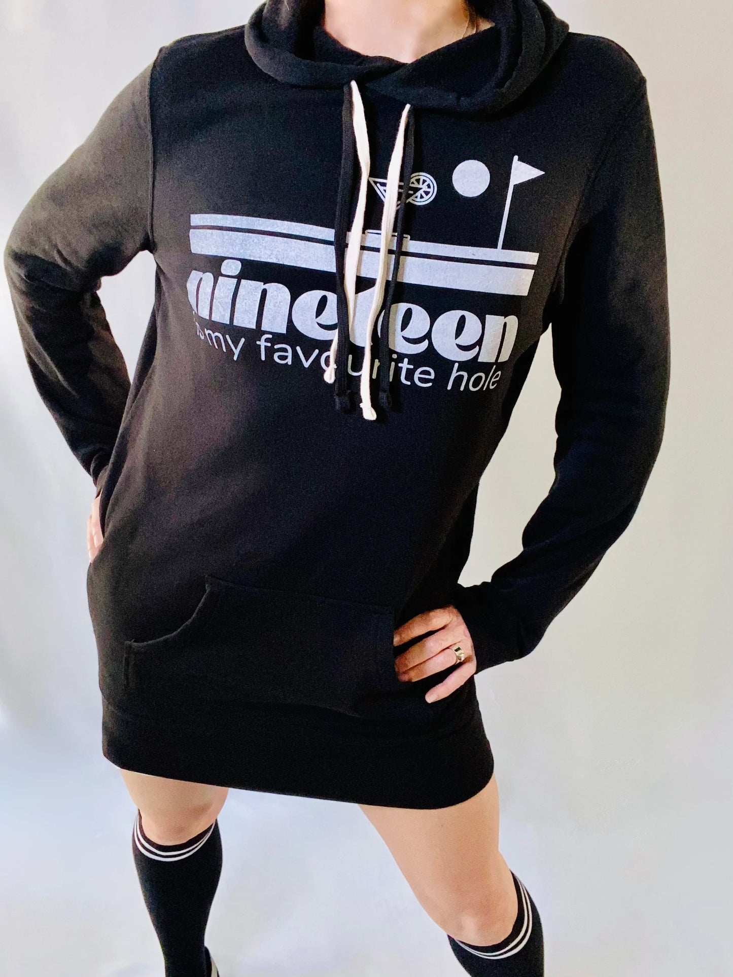 A woman wearing a Nineteenth hole sweatshirt dress by Golf Garter with knee-high socks.